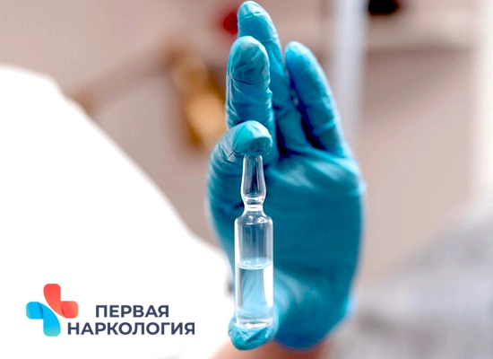 Рука в медицинской перчатке держит ампулу с лекарством